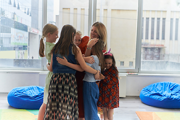 Image showing A child hugging a teacher in a modern kindergarten