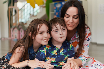 Image showing A girl and a woman hug a child with down syndrome in a modern preschool institution