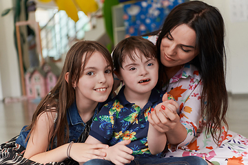 Image showing A girl and a woman hug a child with down syndrome in a modern preschool institution