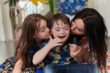 Image showing A girl and a woman hug a child with down syndrome in a modern preschool institution