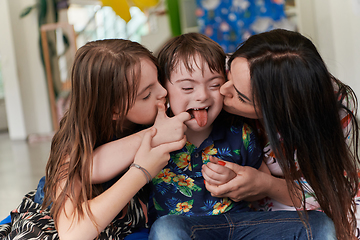 Image showing A girl and a woman hug a child with down syndrome in a modern preschool institution