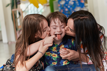 Image showing A girl and a woman hug a child with down syndrome in a modern preschool institution