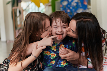 Image showing A girl and a woman hug a child with down syndrome in a modern preschool institution
