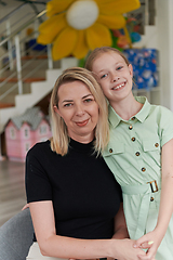 Image showing A cute little girl kisses and hugs her mother in preschool