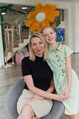 Image showing A cute little girl kisses and hugs her mother in preschool