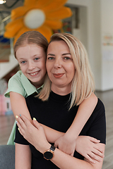 Image showing A cute little girl kisses and hugs her mother in preschool