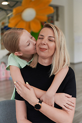 Image showing A cute little girl kisses and hugs her mother in preschool