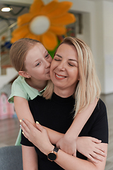 Image showing A cute little girl kisses and hugs her mother in preschool