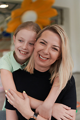 Image showing A cute little girl kisses and hugs her mother in preschool