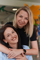 Image showing Two women share a heartfelt embrace while at a preschool, showcasing the nurturing and supportive environment for learning and growth