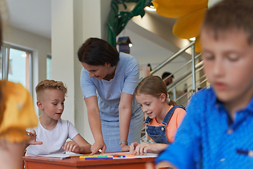 Image showing Creative kids during an art class in a daycare center or elementary school classroom drawing with female teacher.