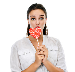 Image showing Candy, portrait and happy woman with a lollipop in a studio for a sweets craving, dessert or sugar. Happiness, snack and young female model eating heart shape sweet while isolated by white background