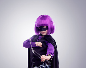 Image showing Kid, costume girl or vigilante in studio portrait with nunchaku, fantasy or creative comic clothes. Kid, superhero aesthetic, mask and creative for martial arts, villain or cosplay by gray background