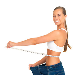 Image showing Portrait, waist and weight loss with a woman measuring her tummty in studio isolated on a white background. Fitness, diet and health with a female holding a tape measure to track her weightloss