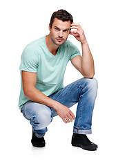 Image showing Fashion, attitude and portrait of man on a white background in trendy, casual and stylish clothes. Confidence, handsome and isolated male fashion model kneel in studio in urban, retro and 2000s style