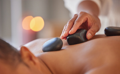 Image showing Spa, man and stone massage to relax, wellness and health for body care, peace or holistic care. Male, gentleman or lying on table at luxury resort, zen or therapy for skincare with rocks