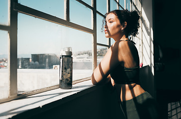 Image showing Window, fitness and relax with a sports woman looking at the view during a break in the gym for exercise. Health, wellness and training with a female athlete taking a break from her studio workout