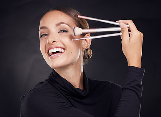 Image showing Makeup, brush or portrait of woman in studio with beauty cosmetics or facial foundation products on black background. Makeup artist, smile or happy girl brushes face for luxury skincare grooming