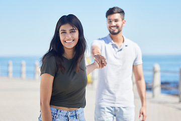 Image showing Beach, love and portrait of a happy couple holding hands while on a seaside summer vacation. Happiness, smile and young man and woman from India walking on the promenade by the ocean while on holiday