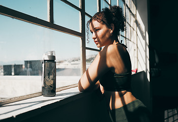 Image showing View, exercise and relax with a sports woman looking out of a window during a break in the gym for fitness. Health, wellness and training with a female athlete taking a break from her studio workout