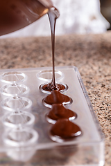 Image showing Baker pours chocolate