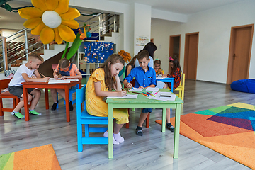 Image showing Creative kids during an art class in a daycare center or elementary school classroom drawing with female teacher.