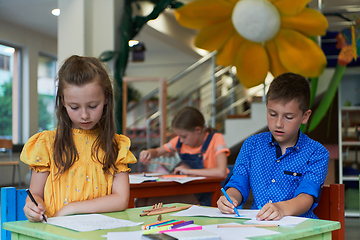 Image showing Cute girl and boy sit and draw together in preschool institution