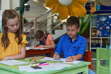 Image showing Cute girl and boy sit and draw together in preschool institution