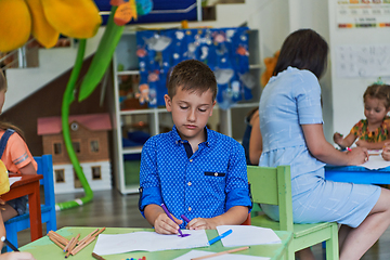 Image showing Creative kids during an art class in a daycare center or elementary school classroom drawing with female teacher.