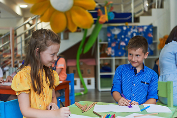 Image showing Cute girl and boy sit and draw together in preschool institution