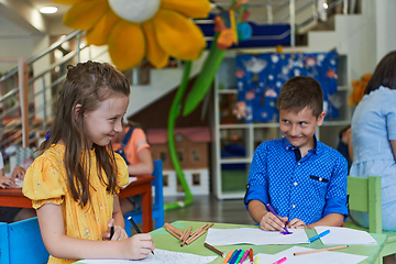 Image showing Cute girl and boy sit and draw together in preschool institution