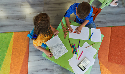 Image showing Cute girl and boy sit and draw together in preschool institution