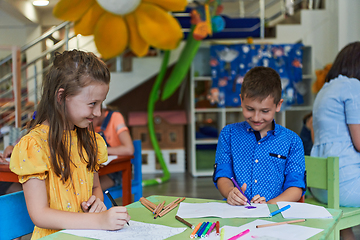 Image showing Cute girl and boy sit and draw together in preschool institution