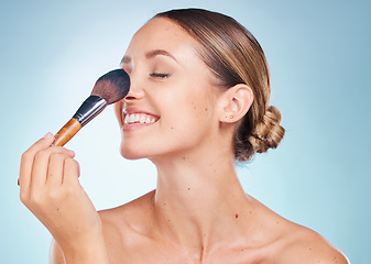 Image showing Woman, face and smile with makeup brush for skincare beauty, dermatology wellness and cosmetics treatment in blue background. Model happiness, facial care and luxury product application in studio