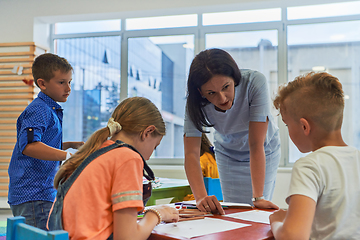 Image showing Creative kids during an art class in a daycare center or elementary school classroom drawing with female teacher.