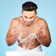 Image showing Face, water splash and skincare of man cleaning in studio isolated on a blue background. Hygiene, water drops and male model washing, bathing or grooming for healthy skin, facial wellness or beauty.