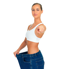 Image showing Health, weight loss and woman pointing hand with jeans and tummy tuck with skinny waist, isolated on white background. Smile, healthcare and wellness, happy girl with liposuction, diet and big pants.