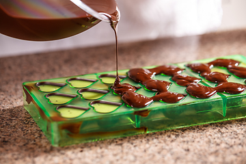 Image showing Pouring chocolate in mold