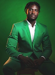 Image showing Fashion, formal and black man in a green suit sitting on a chair in studio with a luxury outfit. Elegant, stylish and portrait of an African male model with fashionable clothes isolated by background