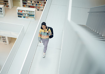 Image showing Top view, woman and walking in library, college and education for knowledge, intelligence and smart. Female, student and girl with backpack, university and bookshelf for test, casual or trendy person