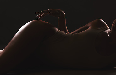 Image showing Lingerie, shadow and silhouette of sexy woman relax in erotic, sexual and seductive underwear on dark black background. Sexuality, creativity and body of aesthetic model girl with creative beauty