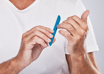 Image showing Hands, nail file and grooming with a man in studio on a gray background for beauty while filing his finger nails. Manicure, wellness and cosmetics with a male taking care of his personal hygiene