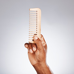 Image showing Hand, wood comb and studio for beauty, grooming and self care cosmetics by grey background. Black man, organic wooden product and recycle material for wellness, skincare and hair care with self love