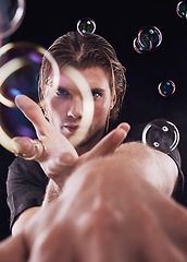 Image showing Man hands, bubbles and magic portrait in studio for art performance, creative show and black background. Model focus, magician and soap with rainbow light, dark aesthetic or theater presentation