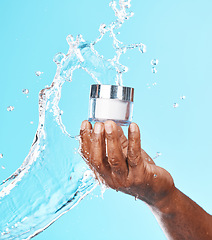 Image showing Hand, water splash and black man with cream for skincare in studio on a blue background. Cosmetics, hygiene and male model holding lotion, creme or moisturizer product for healthy skin and beauty.