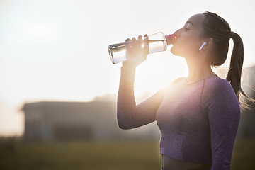 Image showing Fitness, sunset and woman drinking water bottle after training workout, exercise and outdoor cardio running. Thirsty young athlete, sports hydration and nutrition for wellness, healthy body or energy