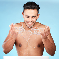 Image showing Face, water splash and skincare of man cleaning in studio isolated on a blue background. Hygiene, water drops and male model washing, bathing or grooming for healthy skin, facial wellness or beauty.