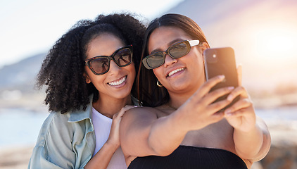 Image showing Women, lgbtq and phone selfie at beach for love, travel and care on summer holiday, vacation or freedom. Sunglasses, lesbian and happy couple of friends taking mobile photograph, sea and social media