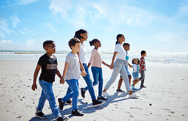 Image showing Summer, children and friends walking on the beach, holding hands together for holiday or vacation. Nature, diversity and walk with a kids group bonding by the sea or ocean in the day for community