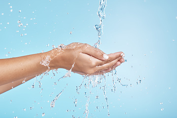 Image showing Woman hands, water splash and clean wellness, skincare and personal hygiene, health and shower on studio blue background. Closeup water drops, stream and washing hands, palm and cleaning body in bath